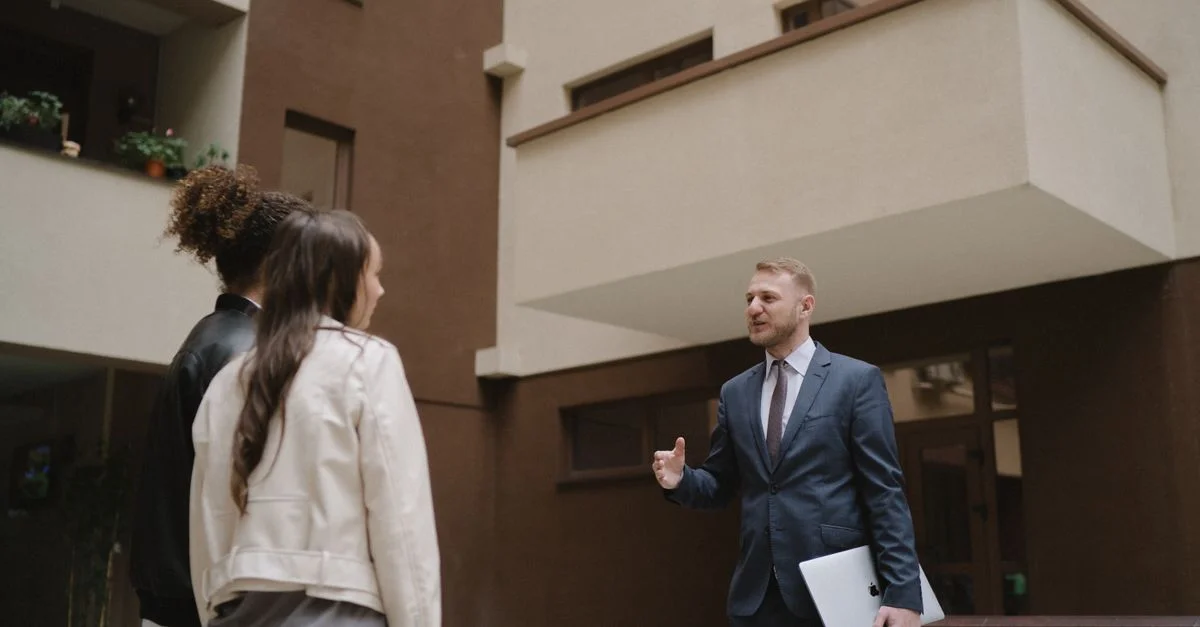 Un agent immobilier montre un appartement à un couple, illustrant une expérience de visite de propriété.
