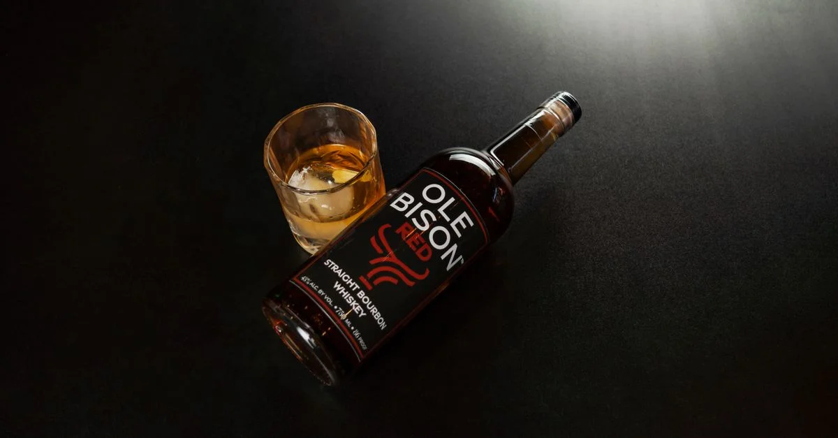 Une bouteille de whisky Ole Bison Straight Bourbon avec un verre sur une surface sombre, La Nouvelle-Orléans.