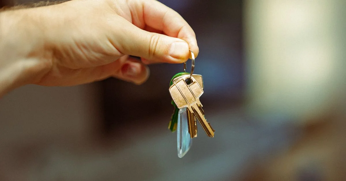 Une image en gros plan d'une main tenant un porte-clés avec plusieurs clés de maison, symbolisant l'immobilier et la propriété.