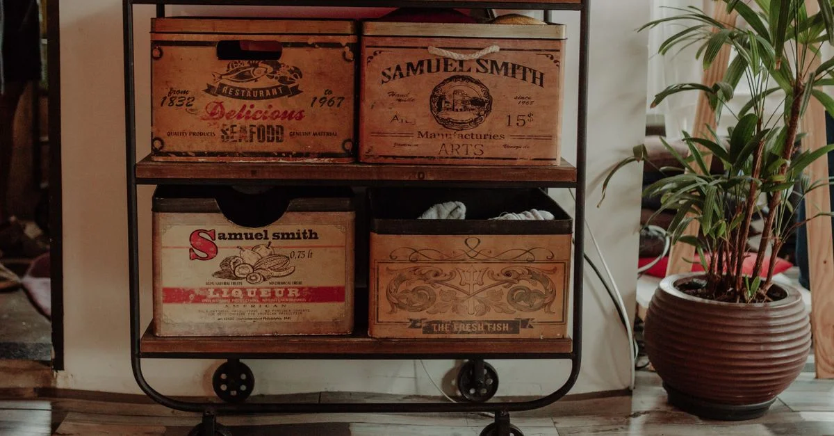 Un chariot industriel élégant avec des caisses en bois vintage à côté d'une plante en pot à l'intérieur.