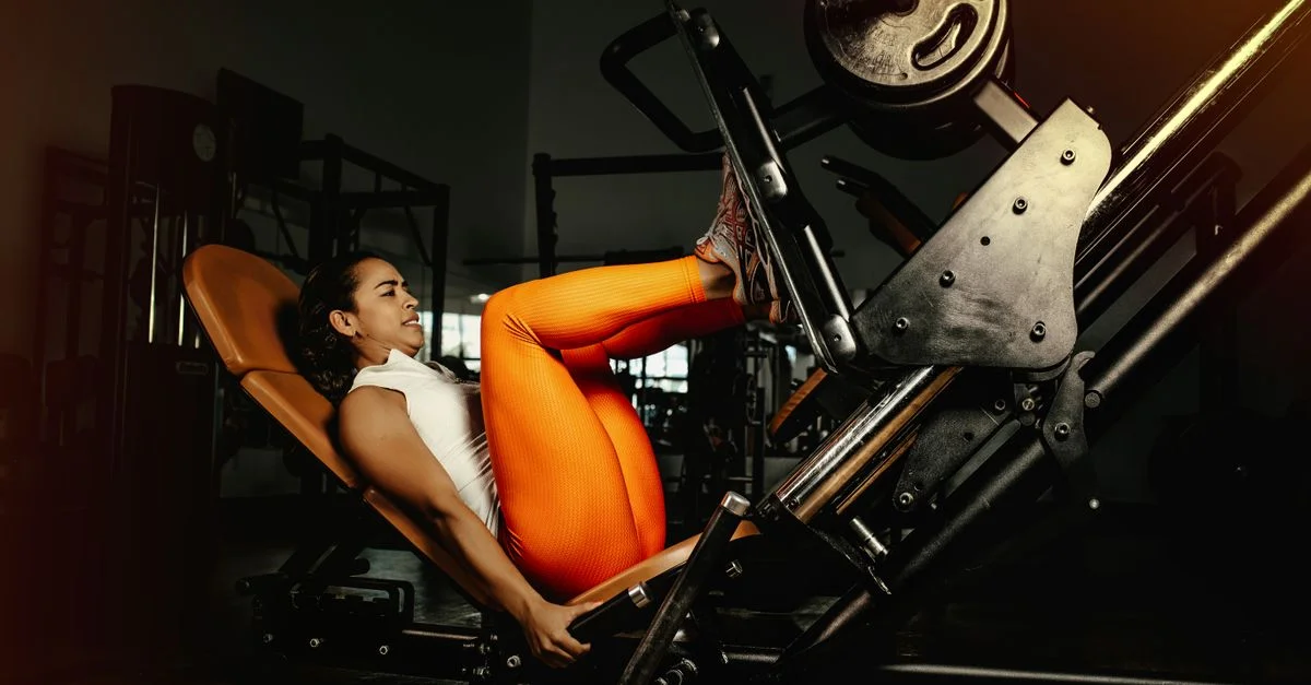 Jeune femme effectuant un exercice de presse des jambes dans un gymnase, démontrant force et forme physique.