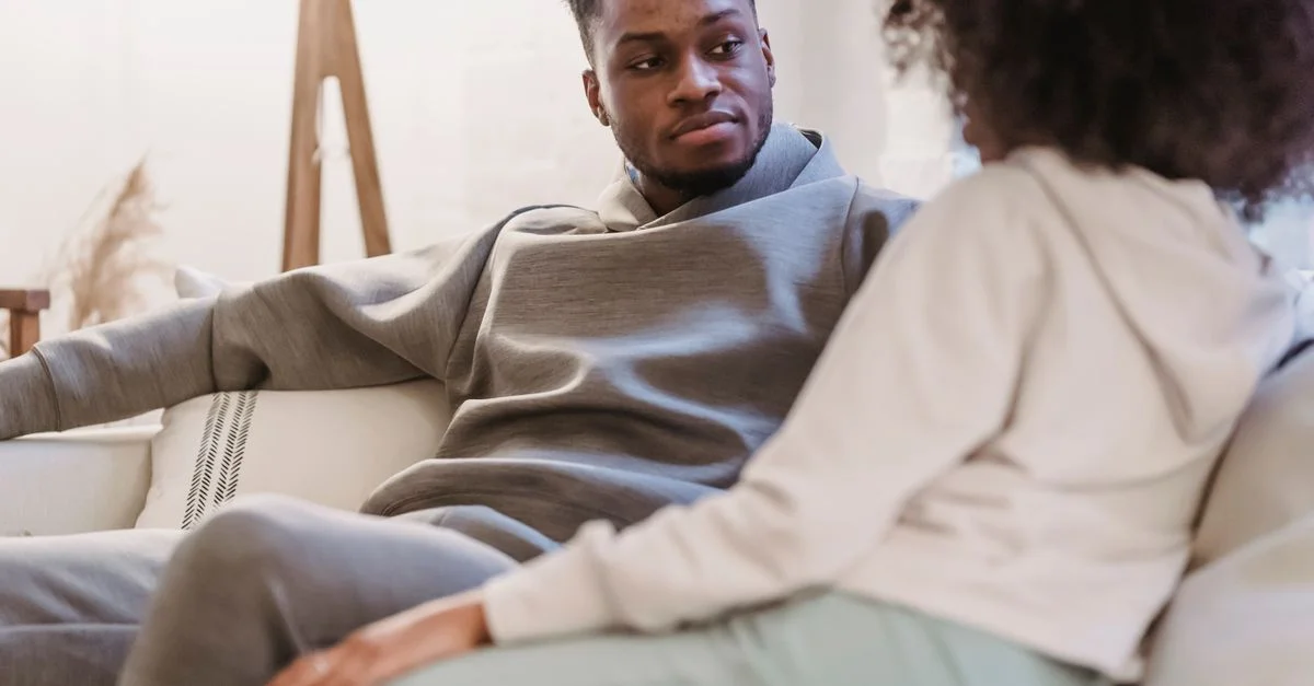 Un couple se détend sur le canapé à la maison, engageant une conversation réfléchie.