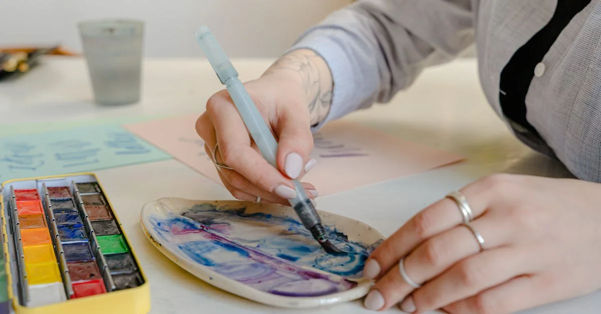 Gros plan d'une femme créant de l'art avec des aquarelles sur une palette dans un cadre de studio.