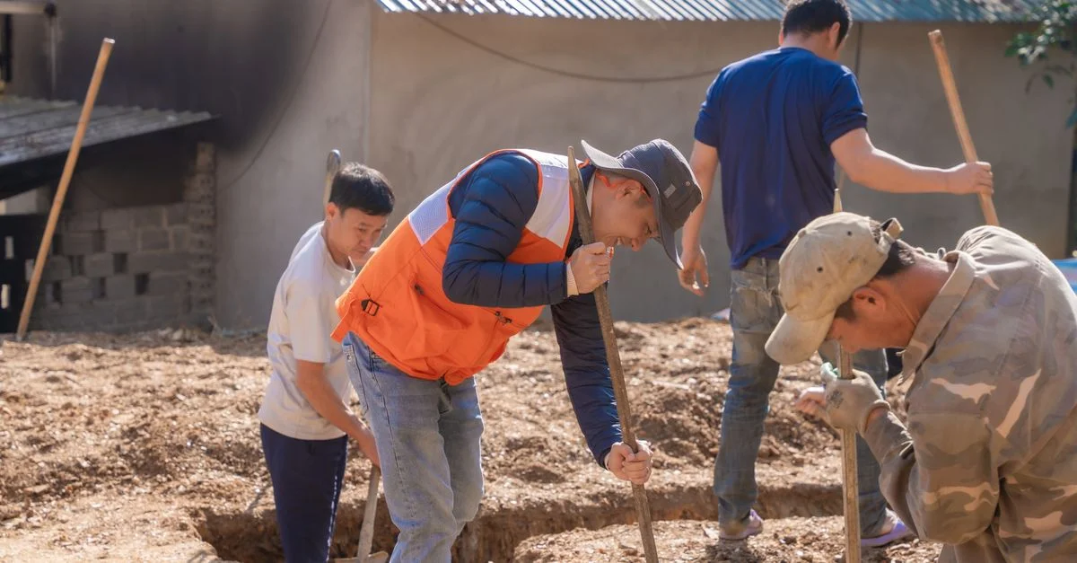 Groupe de travailleurs creusant des tranchées de fondation sur un chantier de construction en extérieur.